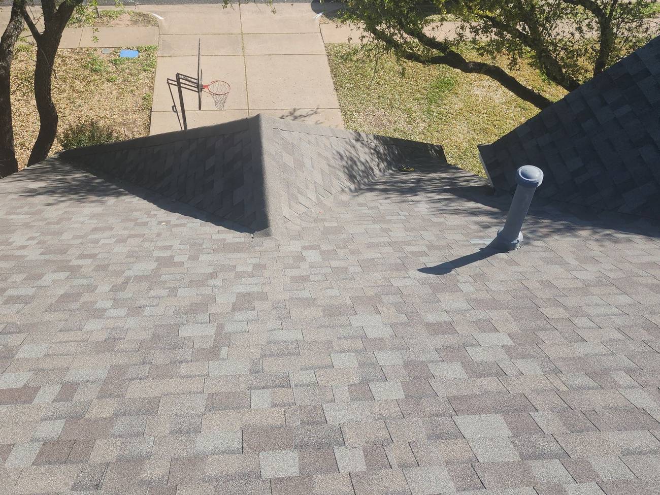 A completed architectural shingle roof on an Austin-area home with new pipe-boot flashing
