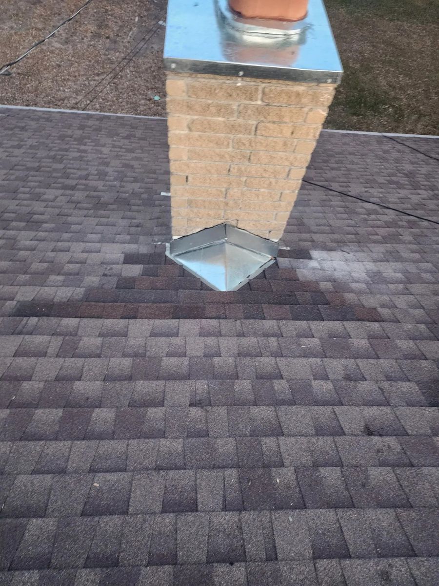 A hand-fabricated galvanized metal cricket diverting water around a brick chimney