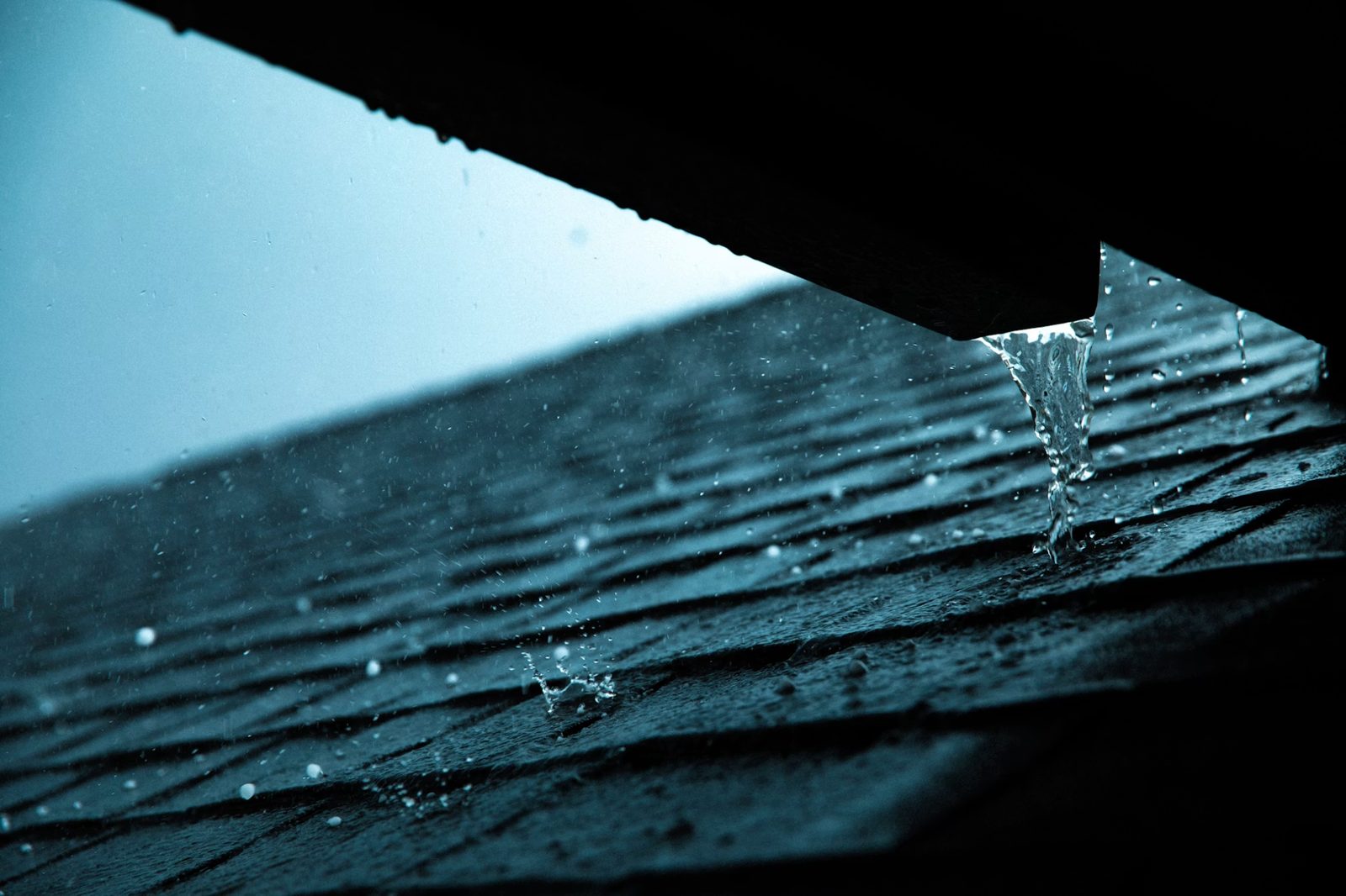 Heavy rain pouring from gutter onto roof