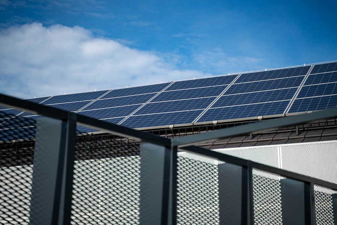 Blue solar panels on a roof against blue clear sky.