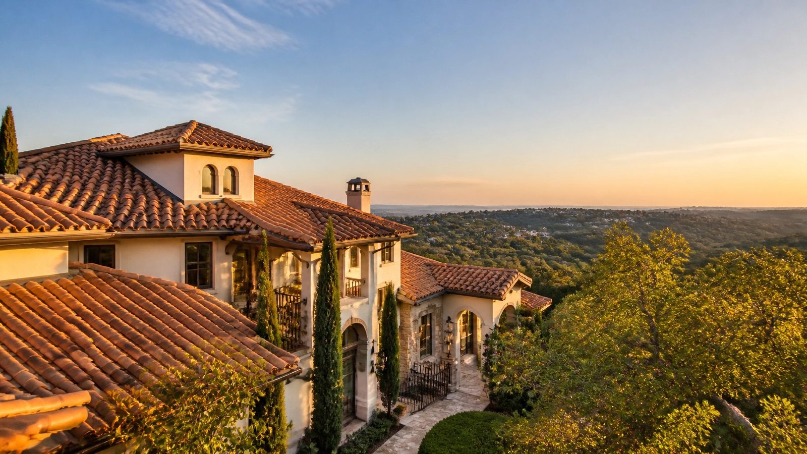 A Spanish-style Austin home with a clay tile roof at sunset overlooking the Hill Country
