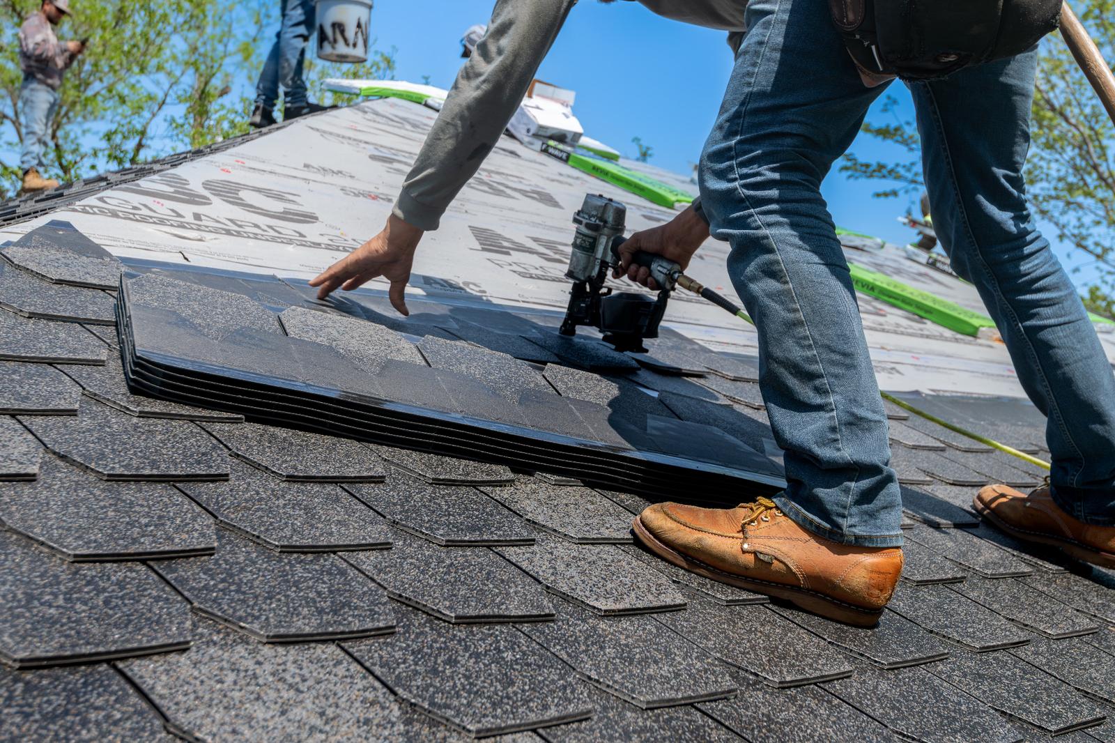 Professional roofers installing shingles on a new roof.