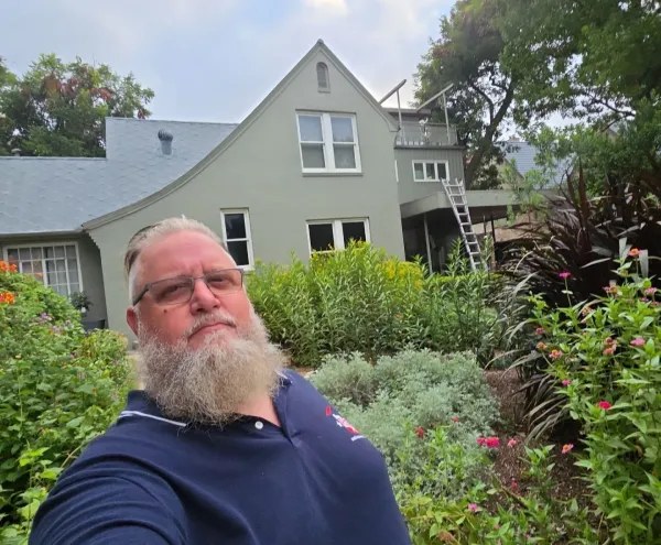 Dennis White, co-founder of Austin Area Roofers, in front of a Central Texas home