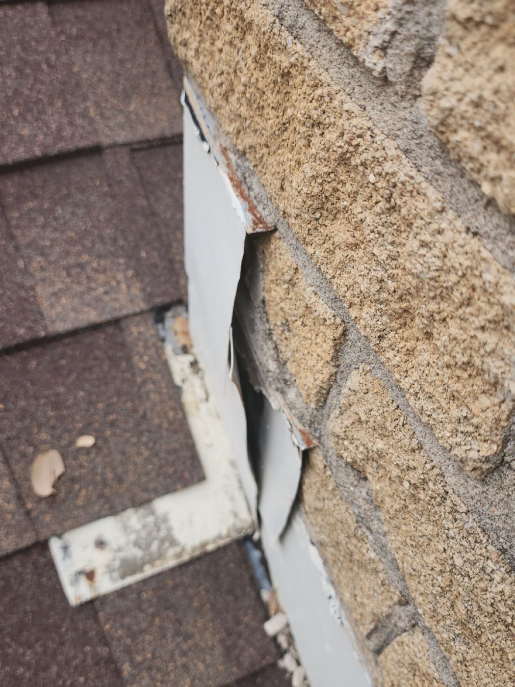 Decayed roof-to-wall step flashing on the Mr. Vasquez El Rey Blvd roof with rust perforation and failed sealant, the failure mode that creates sidewall leaks behind a finished interior.
